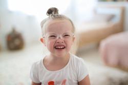 portrait of a toddler girl in glasses in a bright room