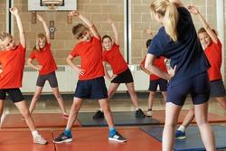 Teacher taking exercise class in school gym